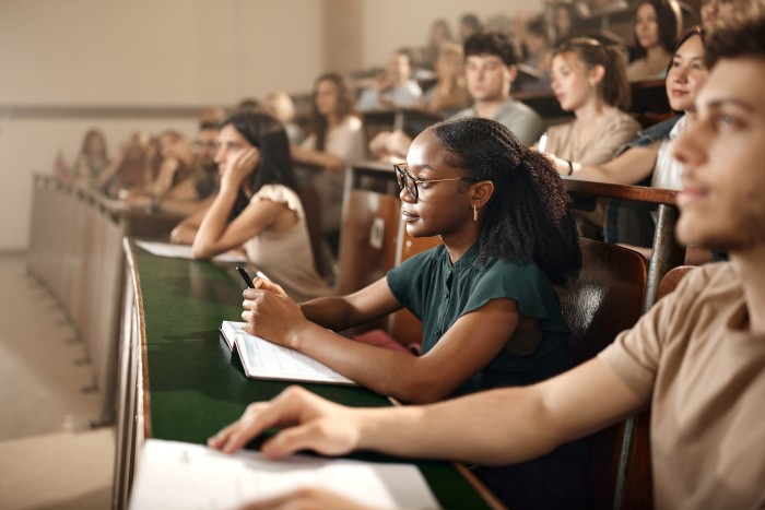 African American female student and her classmates having a class in amphitheater.